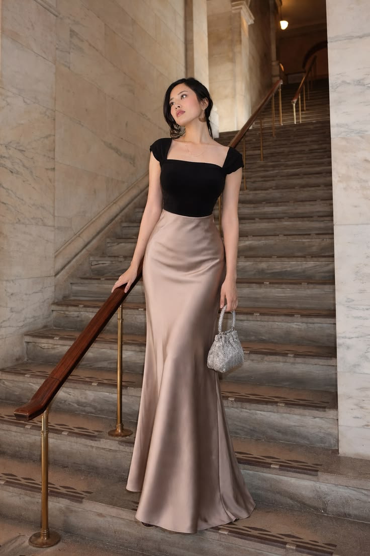 Woman wearing a black top and champagne satin skirt